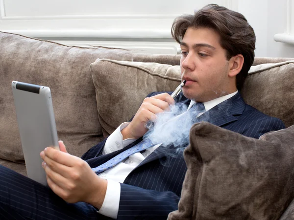 Jeune homme relaxant avec une cigarette électronique — Photo