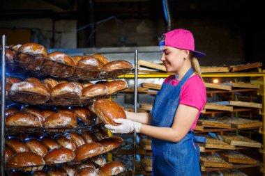 Bir kadın fırıncı fırının işyerindedir. Profesyonel bir fırıncı elinde ekmek tutar. Ekmek üretim konsepti