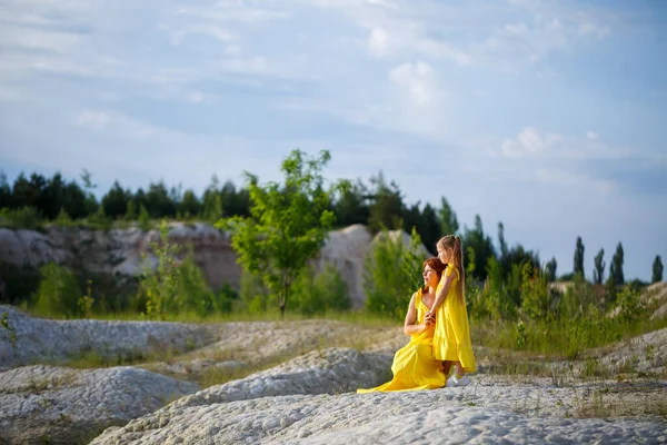 紺碧の水と緑の木々と湖の近くの黄色のドレスで彼女の娘と若い女性 幸せな家族関係の概念 — ストック写真