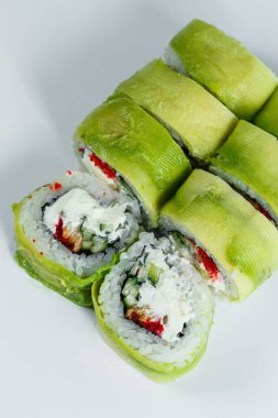 Beyaz arka planda soyutlanmış somonlu Asya suşisi. Avokado, peynir ve kırmızı somon havyarlı Japon yemeği..