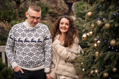 Noel ağacı köknar dalları. Dışarıda Noel ağacı süsleyen genç bir çift. Noel süslemeleri, lolipoplar ve toplar.