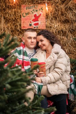 Noel ağacının yanındaki Noel bahçesinde yürüyen genç bir çift.
