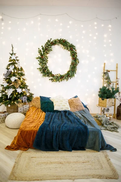 圣诞节的内部是灰色和白色的节日 墙上挂着一个圆形的绿色花环 一张铺着舒适毛毯的床矗立在一座装饰着花环的房子里 — 图库照片