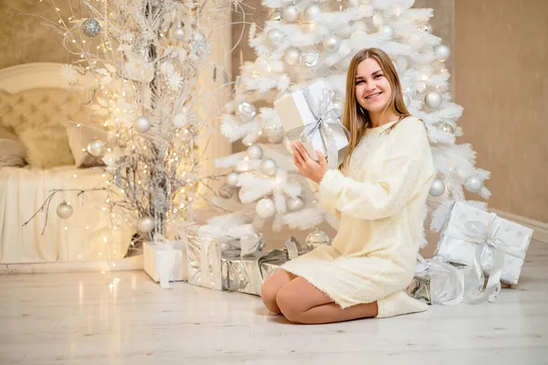 스웨터를 아름다운 금발의 소녀가 크리스마스 선물을 크리스마스 트리로 장식된 침실에 — 스톡 사진
