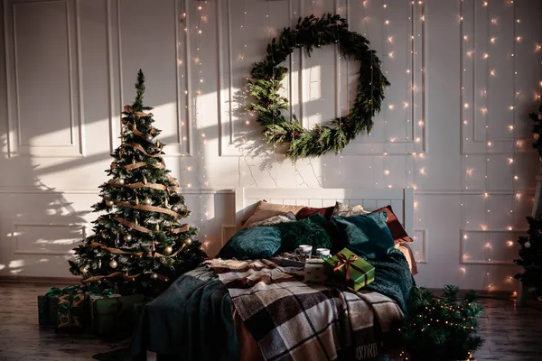 这个卧室是圣诞节装饰的 舒适轻盈的内部 木制床 房间里有一棵圣诞树 上面装饰着玩具和花环 树下的礼物 — 图库照片