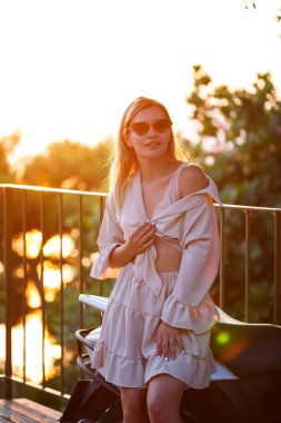 Gün batımında güzel bir kadın denize bakan bir terasta duruyor. Yüksek kalite fotoğraf