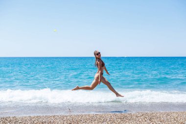 İnce, güzel, mayolu bir kadın deniz kıyısında yürüyor. Yaz tatili kavramı. Seçici odak