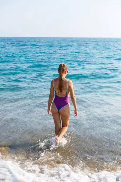 ブロンドの髪の若い女性がポーズをとって海に休んでいます 島の観光客の美しい運動体 選択的焦点 — ストック写真