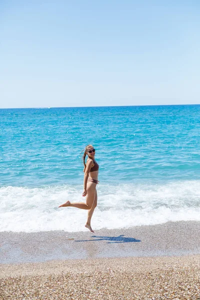 İnce, güzel, mayolu bir kadın deniz kıyısında yürüyor. Yaz tatili kavramı. Seçici odak