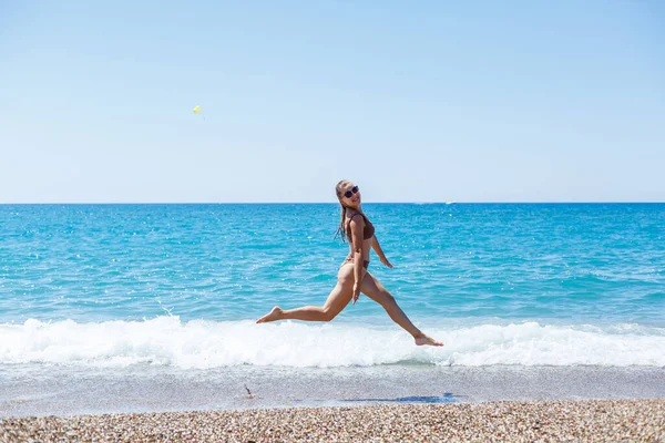 İnce, güzel, mayolu bir kadın deniz kıyısında yürüyor. Yaz tatili kavramı. Seçici odak