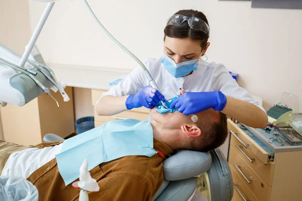 Mężczyzna Siedzi Fotelu Dentystycznym Otrzymuje Regenerację Zębów Kobieta Dentysta Klinice — Zdjęcie stockowe