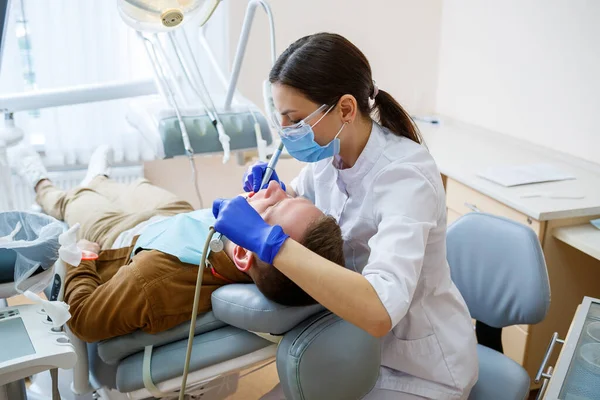 Een Vrouwelijke Tandarts Behandelt Tandbederf Tanden Van Een Mannelijke Patiënt — Stockfoto