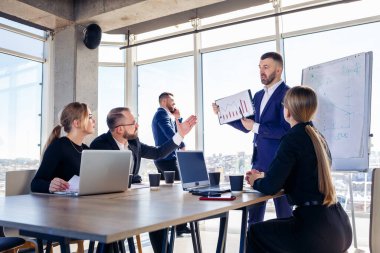 İş adamlarıyla başarılı bir toplantı, yeni iş fikirlerini tartışmak, diyagramlar kullanmak, birlikte oturmak. Modern ofis geçmişi. İş geliştirme konferansında iş ortaklarının toplantısı