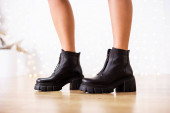 Új női cipők kollekciója 2022 őszén és telén. A lány új cipőt vett. Láb fekete csizmában.