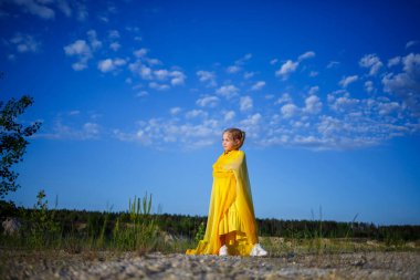 Şirin kıvırcık, güzel, sarışın, doğada sarı bir elbisesi olan kız.