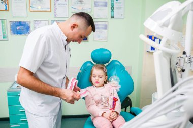 Profesyonel doktor, pediatrik dişçi çocuklara dişlerini fırçalamayı öğretir. Hasta muayenesi için dişçi ofisi. Bir çocukta diş tedavisi süreci.
