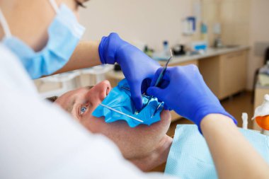 Erkek hasta dişçi koltuğuna oturur ve dişlerini yeniler, dişçi kliniğinde kadın dişçiye gider. Seçici odak