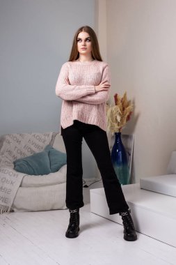 Siyah kot pantolon ve şık ayakkabıları olan şık giyinmiş güzel bir genç kadın. Deri çizmeler içinde güzel kadın bacakları