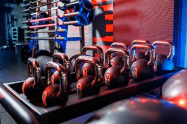 Farklı renklerde kettlebell 'ler. Spor salonundaki spor aletleri. Beden eğitimi için kettlebell. Spor salonunda sıralanmış ağırlık atışları..