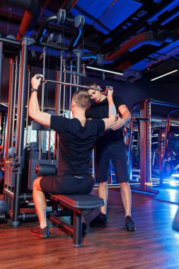 Profesyonel bir antrenörün gözetiminde spor salonunda ağır sırt egzersizleri yapan güçlü bir erkek. Sağlıklı yaşam tarzı