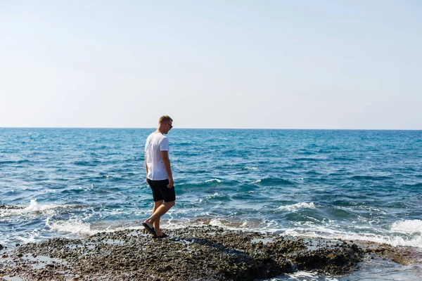 Young Attractive Man Sunglasses White Shirt Shorts Stands Shore Mediterranean — Φωτογραφία Αρχείου