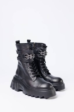 Beyaz arka planda kadın ayakkabıları. Beyaz arka planda tokaları olan siyah kadın deri botlarının yakın çekimi. Şehrin ayakkabıları. 2022 moda, tasarım ve ayakkabı kavramı.