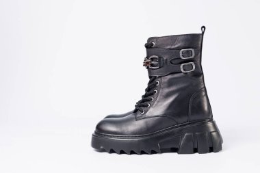 Beyaz arka planda kadın ayakkabıları. Beyaz arka planda tokaları olan siyah kadın deri botlarının yakın çekimi. Şehrin ayakkabıları. 2022 moda, tasarım ve ayakkabı kavramı.