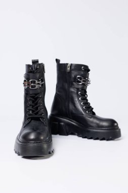 Beyaz arka planda kadın ayakkabıları. Beyaz arka planda tokaları olan siyah kadın deri botlarının yakın çekimi. Şehrin ayakkabıları. 2022 moda, tasarım ve ayakkabı kavramı.