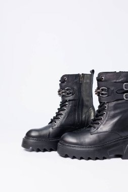 Beyaz arka planda kadın ayakkabıları. Beyaz arka planda tokaları olan siyah kadın deri botlarının yakın çekimi. Şehrin ayakkabıları. 2022 moda, tasarım ve ayakkabı kavramı.