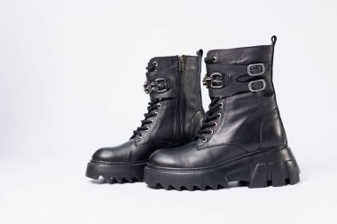 Beyaz arka planda kadın ayakkabıları. Beyaz arka planda tokaları olan siyah kadın deri botlarının yakın çekimi. Şehrin ayakkabıları. 2022 moda, tasarım ve ayakkabı kavramı.