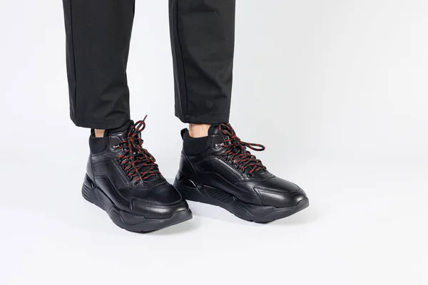 男性の足の白い背景にスタイリッシュな革の黒の短い男性の秋のスニーカー スニーカー冬コレクション2022 — ストック写真