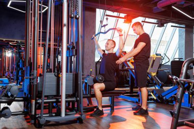 Profesyonel bir antrenörün gözetiminde spor salonunda ağır sırt egzersizleri yapan güçlü bir erkek. Sağlıklı yaşam tarzı