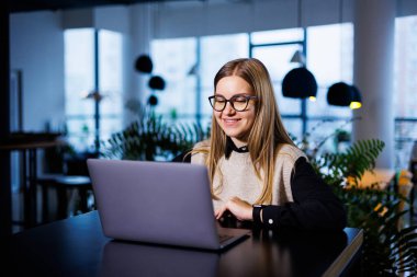Büyük bir şirketin güzel, çekici ve zarif sahibi uluslararası iş ortaklarıyla çevrimiçi bir toplantı yapıyor. İş yerindeki masasında oturuyor.