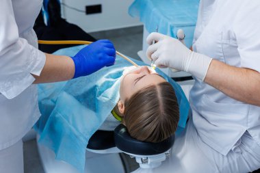 Diş hekimi diş malzemesi kullanarak hastanın dişlerini muayene eder. Modern tıbbi ekipmanlar. Lokal anestezi ile dişlerin anestezisi. Oral tedavi kavramı. Yakın plan. Seçici odak.