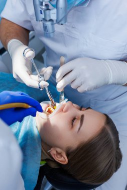 Diş hekimi diş malzemesi kullanarak hastanın dişlerini muayene eder. Modern tıbbi ekipmanlar. Lokal anestezi ile dişlerin anestezisi. Oral tedavi kavramı. Yakın plan. Seçici odak.