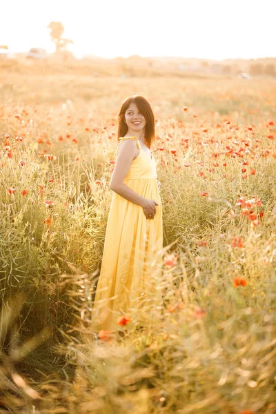 夏天的一天 穿着黄色衣服的美丽的年轻女子在罂粟田里散步 在乡间欣赏花朵的女孩 有选择的重点 — 图库照片