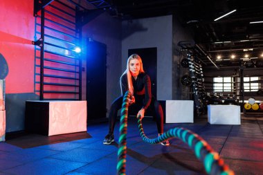 Sportif bir kadın spor malzemelerini kullanarak egzersiz yapar. İp, spor salonuna gider..