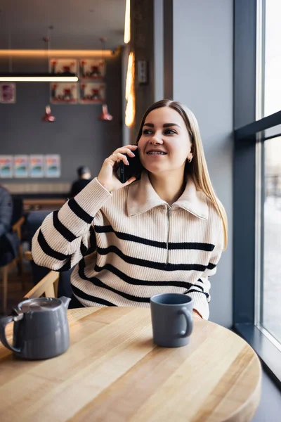 Молодая Привлекательная Женщина Разговаривает Мобильному Телефону Улыбается Сидя Одна Кафе — стоковое фото
