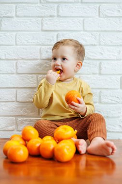 Tatlı gülümseyen çocuk taze mandalina yiyor.