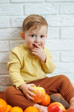 Gülümseyen çocuk taze, sulu bir kırmızı elma yer. Küçük çocuklar için sağlıklı meyveler. Çocuk meyve ve sebze yiyor..