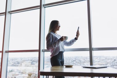 Genç ve başarılı bir kadının portresi telefon görüşmeleri sırasında iş problemlerini çözüyor, modern bir kafede oturuyor. Hoş bir iç mekan, kafede boş vaktinin tadını çıkarıyor..