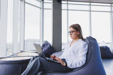 Beyaz gömlekli neşeli, açık renk saçlı bir kadın dizüstü bilgisayarla uzaktan yayın metni yazıyor. Gözlüklü neşeli bir kız netbook 'ta olumlu içerik ve medya dosyalarını paylaşıyor.
