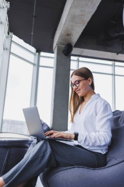 Beyaz gömlekli neşeli, açık renk saçlı bir kadın dizüstü bilgisayarla uzaktan yayın metni yazıyor. Gözlüklü neşeli bir kız netbook 'ta olumlu içerik ve medya dosyalarını paylaşıyor.
