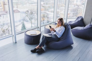 Mutlu gülümseyen bayan yönetici internet uygulaması üzerinden dağıtım hizmetlerini kontrol etmek için cep telefonu aygıtı kullanıyor, kahve dükkanında ücretsiz 4G kablosuz ağ, cep telefonuyla mesajlaşan neşeli serbest çalışan