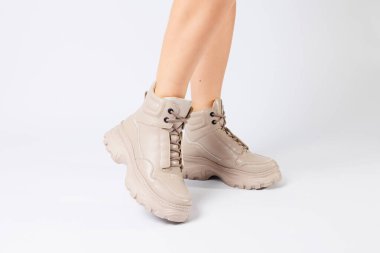 Yeni koleksiyonun bej renkli deri ayakkabıları içindeki kadın bacakları beyaz arka planda kadın bacakları moda olan eko-deri ayakkabılar 2022 baharında..