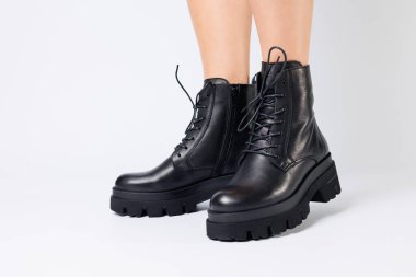 Beyaz arka planda modaya uygun siyah ayakkabılı bir kadın, yakın plan. Şık deri ayakkabılı kadın bacakları.