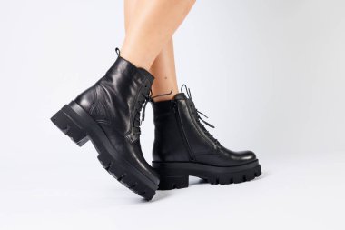 Beyaz arka planda modaya uygun siyah ayakkabılı bir kadın, yakın plan. Şık deri ayakkabılı kadın bacakları.