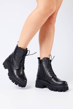 Beyaz arka planda modaya uygun siyah ayakkabılı bir kadın, yakın plan. Şık deri ayakkabılı kadın bacakları.