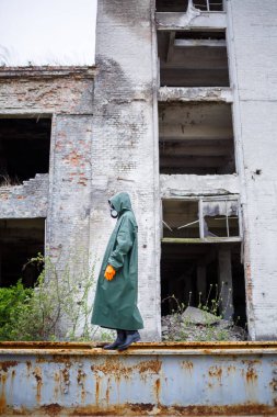 Koruyucu giysiler içinde bir dozimetrist bilim adamı ve gaz maskesi tehlike bölgesindeki radyoaktif radyasyon seviyesini kontrol ediyor. Çevre kirliliği, felaket