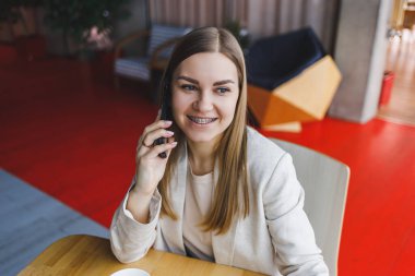 Boş zamanlarında bir kafede tek başına oturan, cep telefonuyla arayan genç ve çekici bir kadın, kafede dinlenirken tatlı bir gülümsemeyle cep telefonuyla konuşan çekici bir kadın.